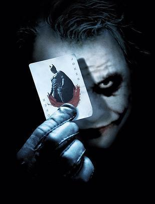 Image of The Joker holding a card with Batman's image on it